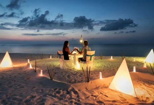 "Romantic beach dinner setup at sunset for couple with ocean view"