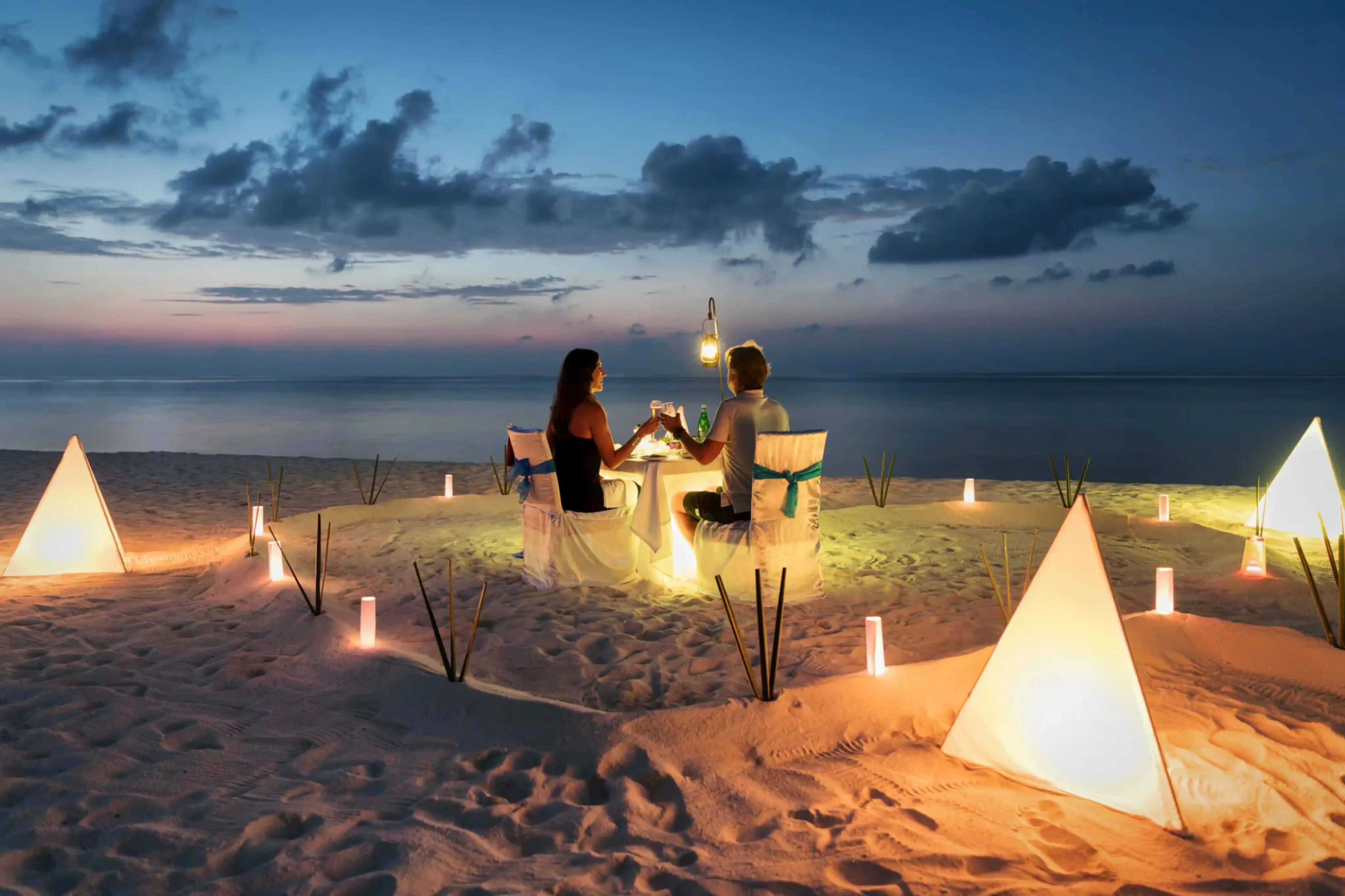"Romantic beach dinner setup at sunset for couple with ocean view"