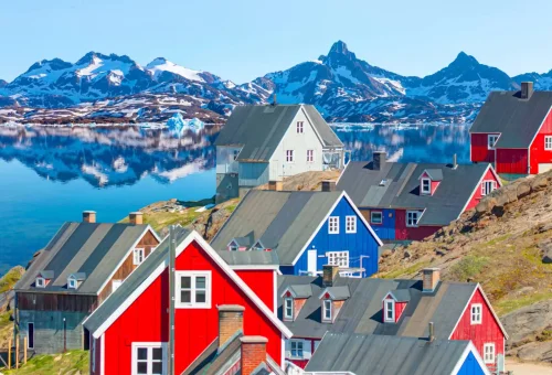 "Colorful houses in Greenland with fjord and snow-capped mountains in background"