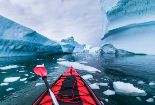 "Adventurous kayaking through icy Arctic waters surrounded by icebergs and glaciers"