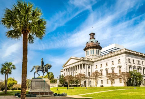 "South Carolina State House with palm trees and statue of General Wade Hampton in Columbia, South Carolina, USA."