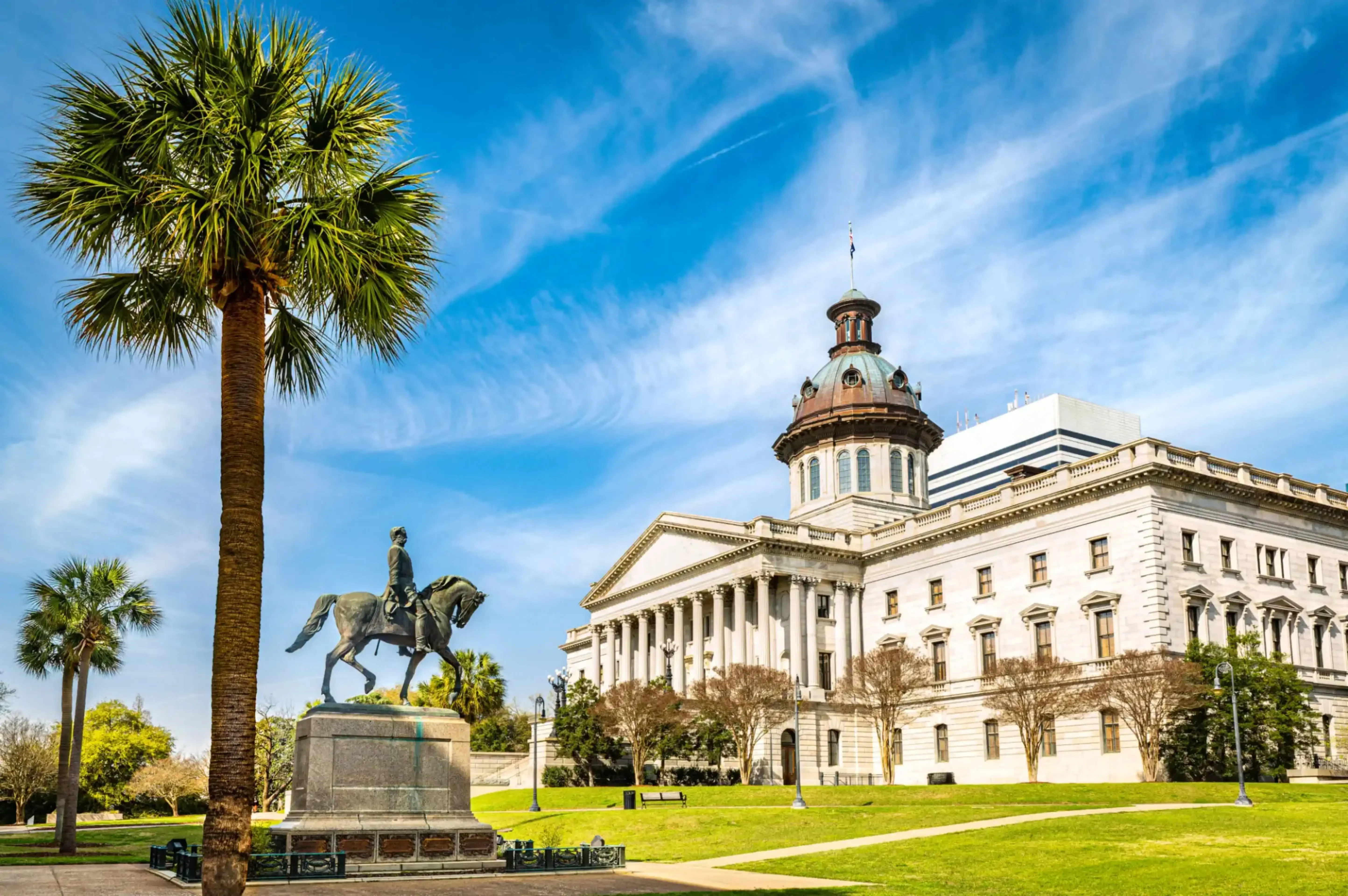 "South Carolina State House with palm trees and statue of General Wade Hampton in Columbia, South Carolina, USA."