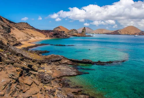 "Bartolomé Island's volcanic coastline and Pinnacle Rock in the Galápagos Islands, Ecuador, with turquoise waters and dramatic rocky terrain."
