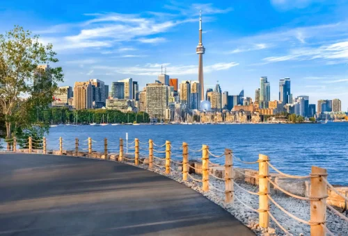 "Toronto skyline with CN Tower viewed from a lakeside boardwalk on a sunny day, Canada."