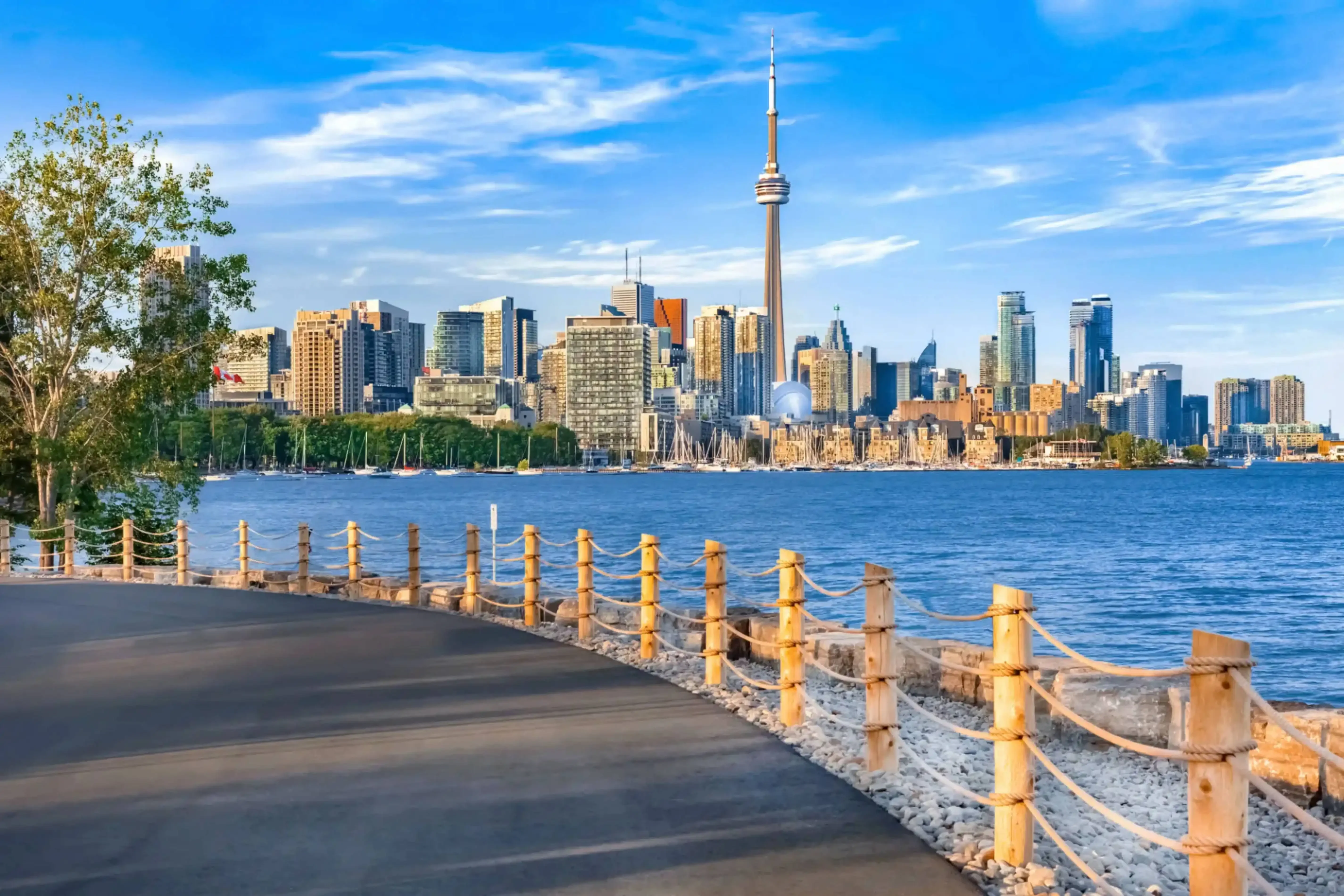"Toronto skyline with CN Tower viewed from a lakeside boardwalk on a sunny day, Canada."