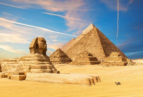 "Great Sphinx and Pyramids of Giza in the desert under a vibrant sky, Egypt."