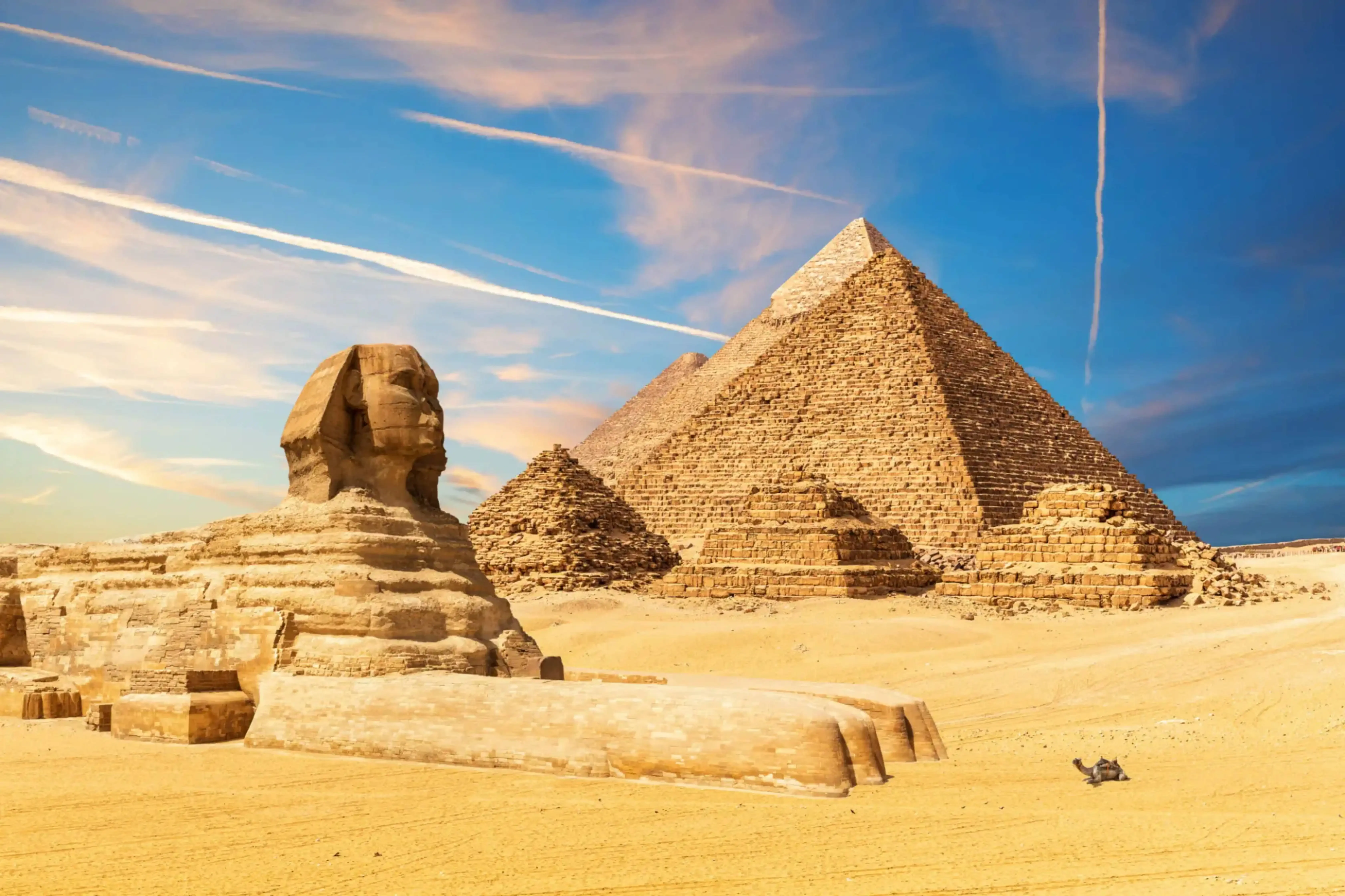 "Great Sphinx and Pyramids of Giza in the desert under a vibrant sky, Egypt."