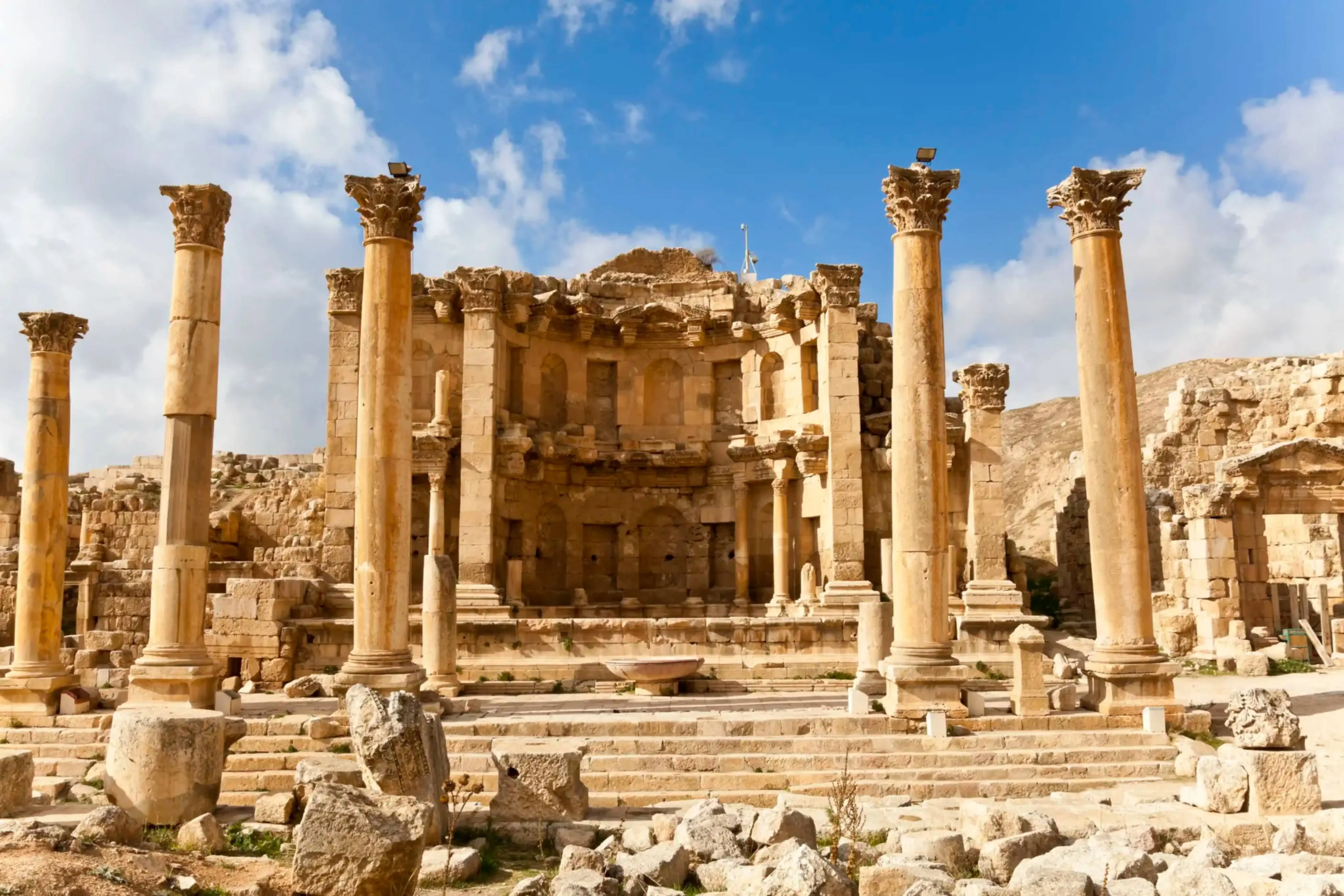 "Ruins of the Roman amphitheater and colonnades at Leptis Magna, Libya, under a bright blue sky."