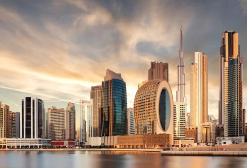 "Modern skyline of Dubai, UAE featuring the Burj Khalifa and circular waterfront skyscrapers during a golden sunset."