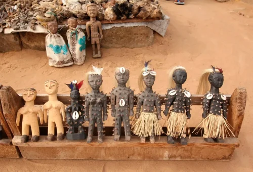 "Traditional African wooden figurines and tribal dolls displayed in a market setting."