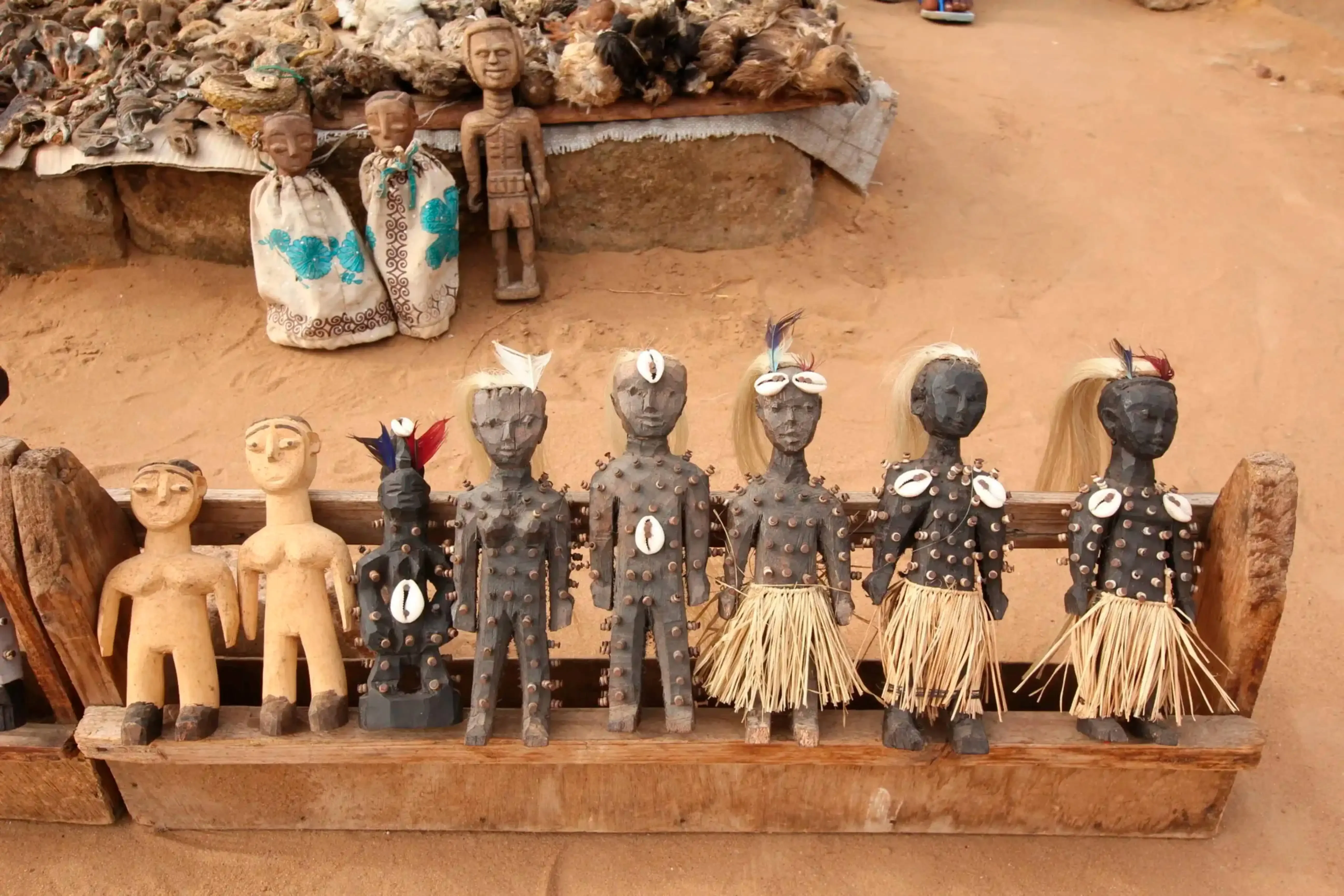 "Traditional African wooden figurines and tribal dolls displayed in a market setting."