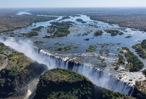 Aerial view of Victoria Falls with cascading water and surrounding lush terrain.