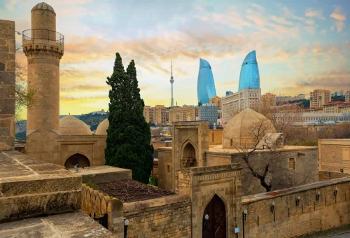 Blend of ancient architecture and modern skyline in Baku, featuring the historic Old City walls and the iconic Flame Towers in the background.