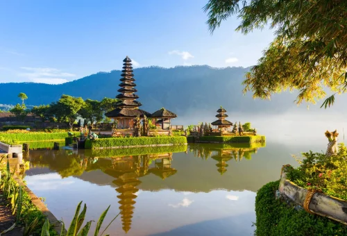 Ulun Danu Beratan Temple in Bali, Indonesia, reflected in the calm waters of Lake Beratan against a scenic mountain backdrop.
