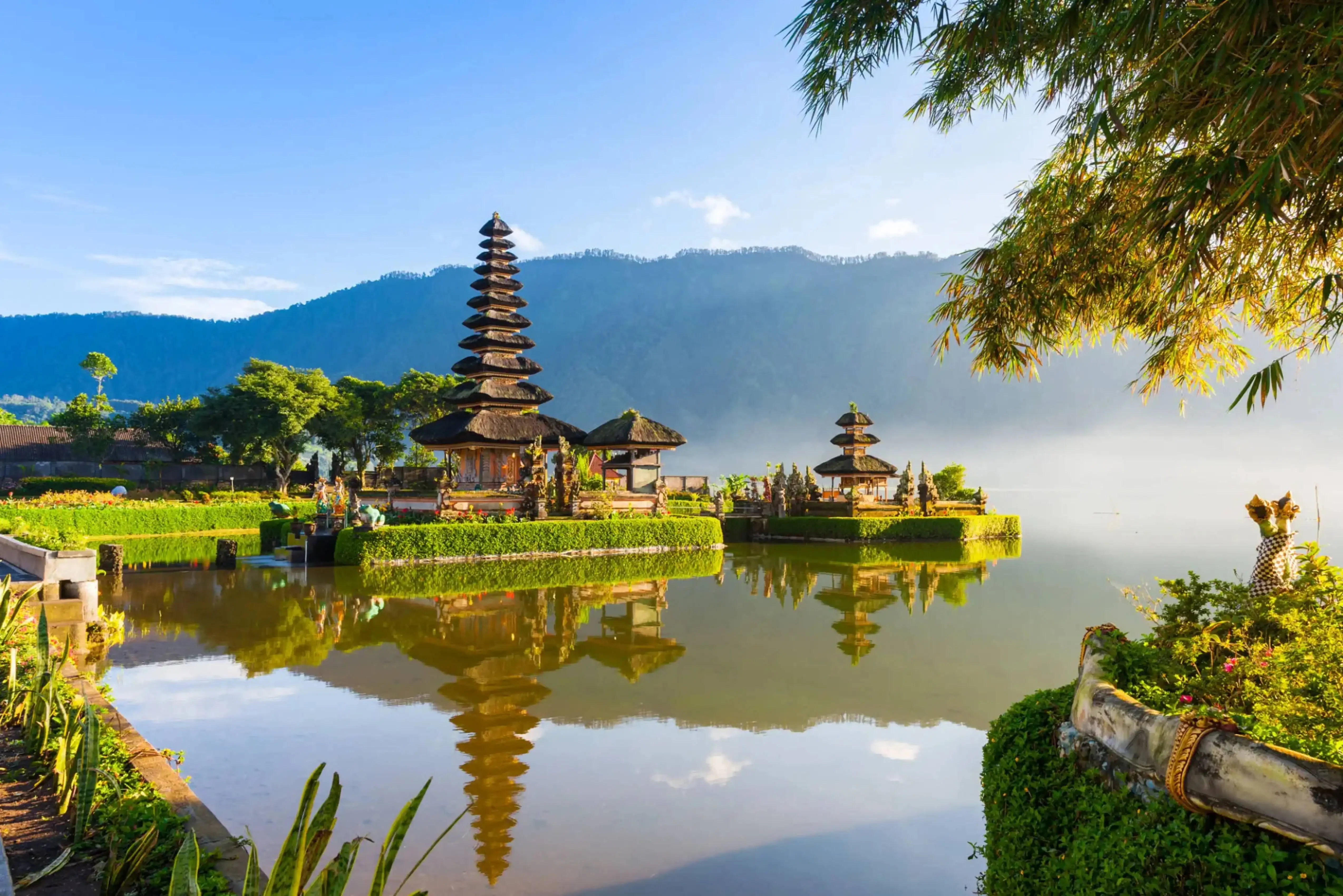 Ulun Danu Beratan Temple in Bali, Indonesia, reflected in the calm waters of Lake Beratan against a scenic mountain backdrop.