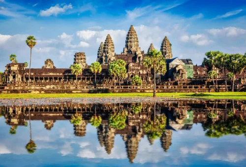 Angkor Wat temple complex reflecting in a tranquil pond under a bright blue sky in Cambodia.