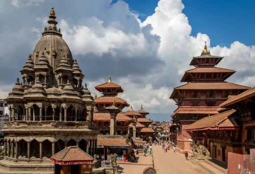Ancient temples and traditional Newari architecture at Patan Durbar Square in Lalitpur, Nepal, under a dramatic cloudy sky.