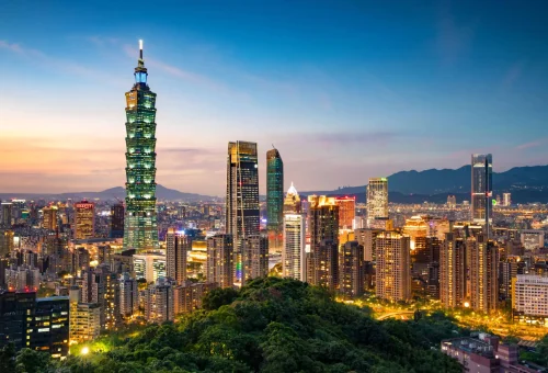 Taipei city skyline at sunset with the iconic Taipei 101 skyscraper prominently visible among surrounding high-rise buildings.
