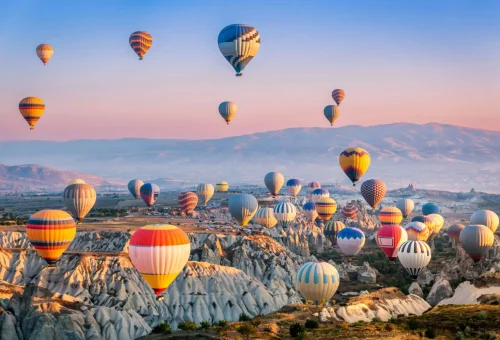 Hot air balloons soaring over the unique rock formations of Cappadocia, Turkey during sunrise.