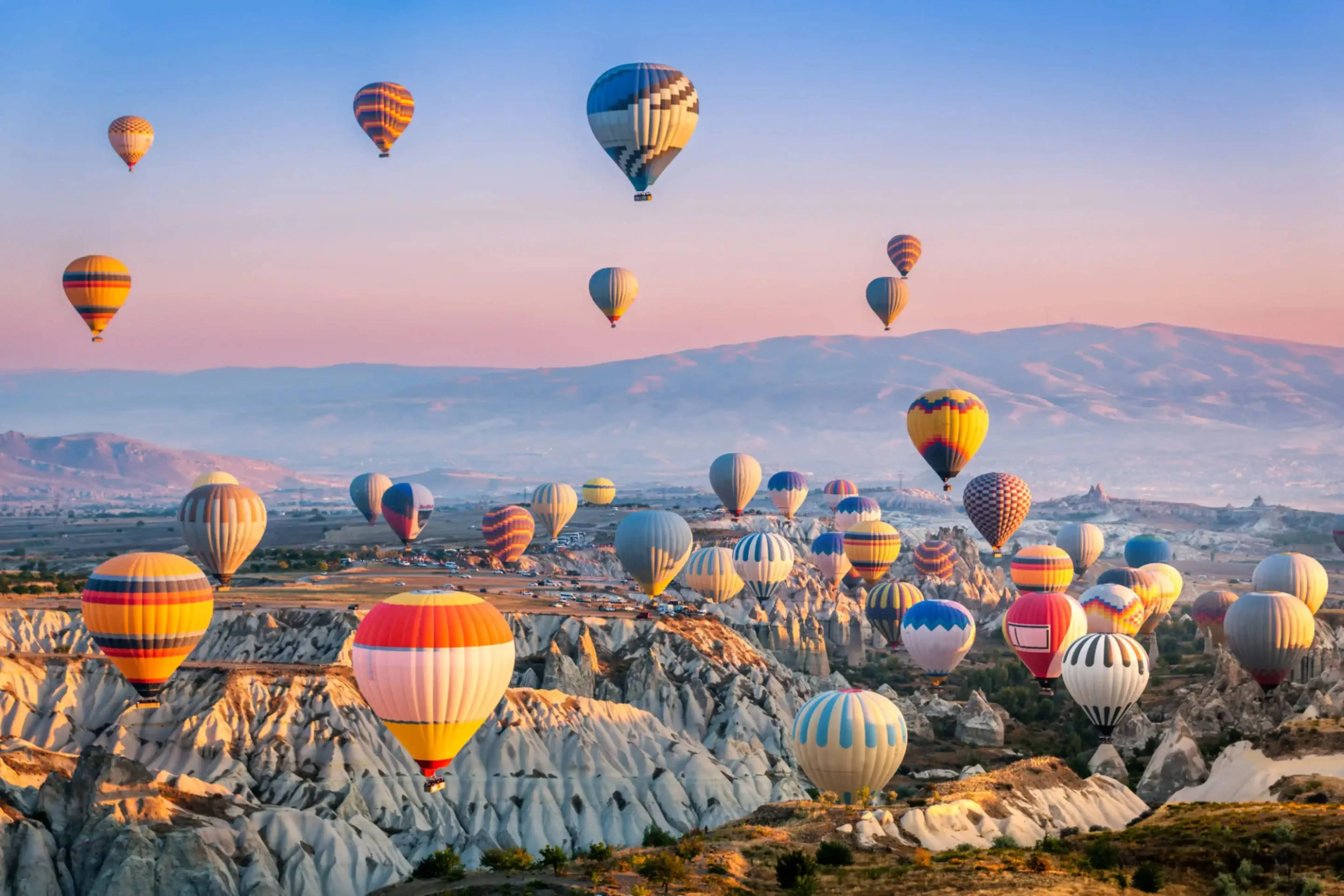 Hot air balloons soaring over the unique rock formations of Cappadocia, Turkey during sunrise.
