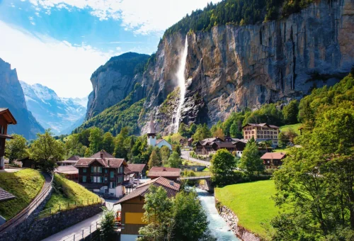 Picturesque village of Lauterbrunnen, Switzerland with traditional Alpine houses and a waterfall cascading down a dramatic cliff.