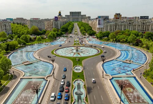 Aerial view of the grand Unirii Boulevard in Bucharest, Romania, featuring symmetrical fountains and landscaped medians leading toward the Palace of the Parliament.