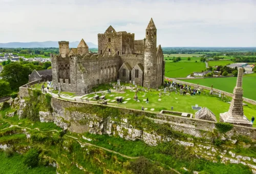 Aerial view of the Rock of Cashel, a historic medieval castle and cathedral ruins atop a green hill in the Irish countryside.