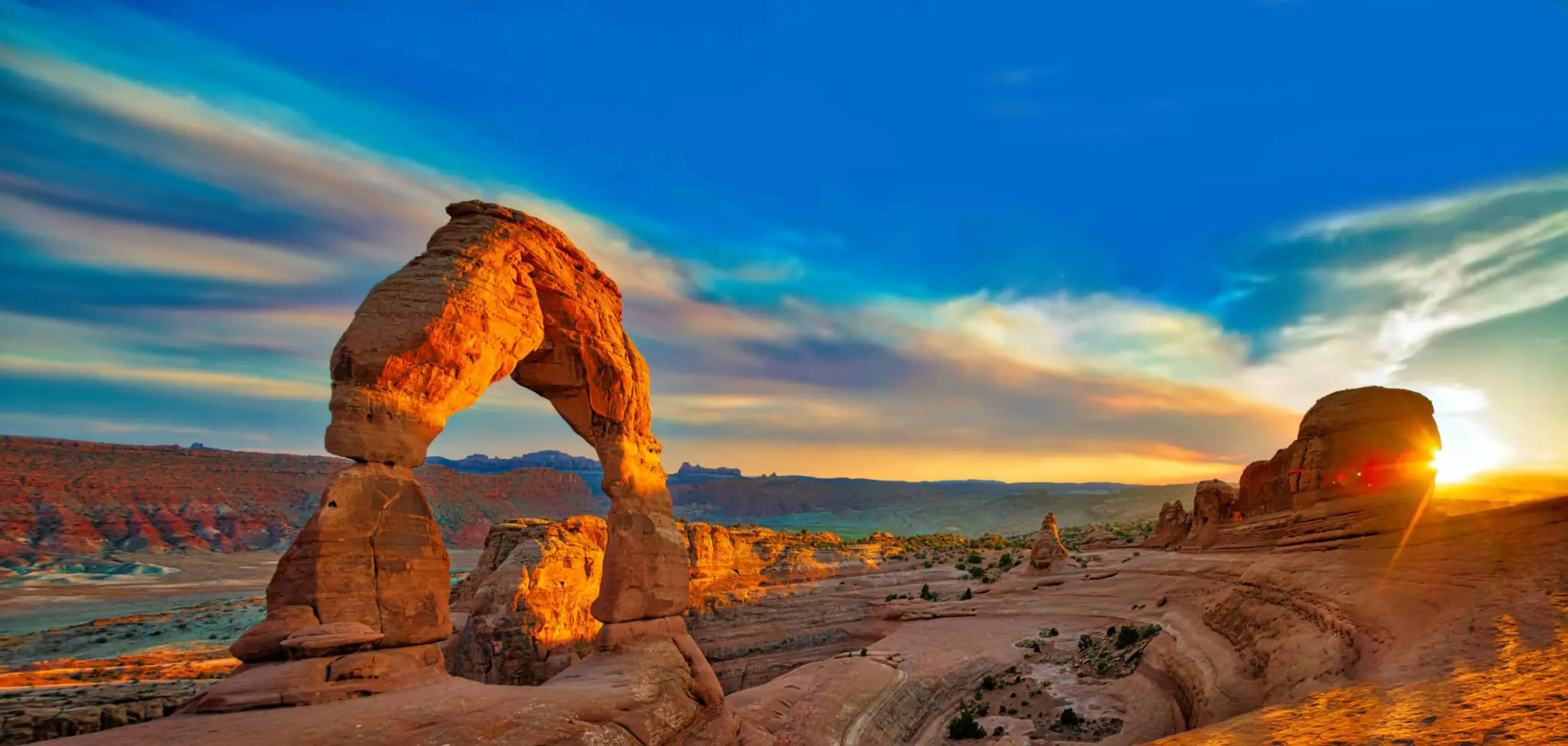 Stunning sunset view of Delicate Arch in Arches National Park, Utah, with vibrant desert landscape and dramatic skies