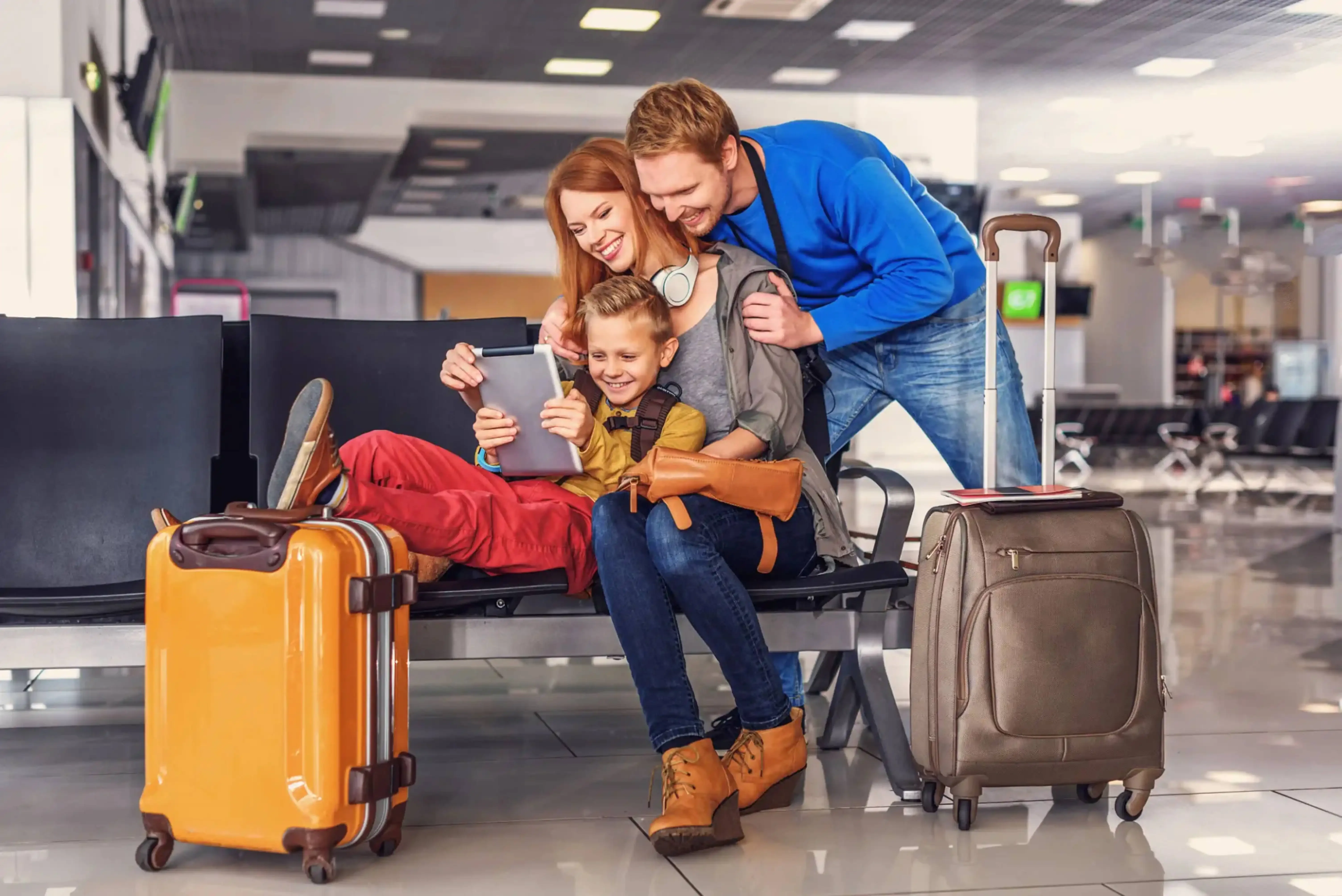 Happy family with luggage watching tablet while waiting at airport terminal