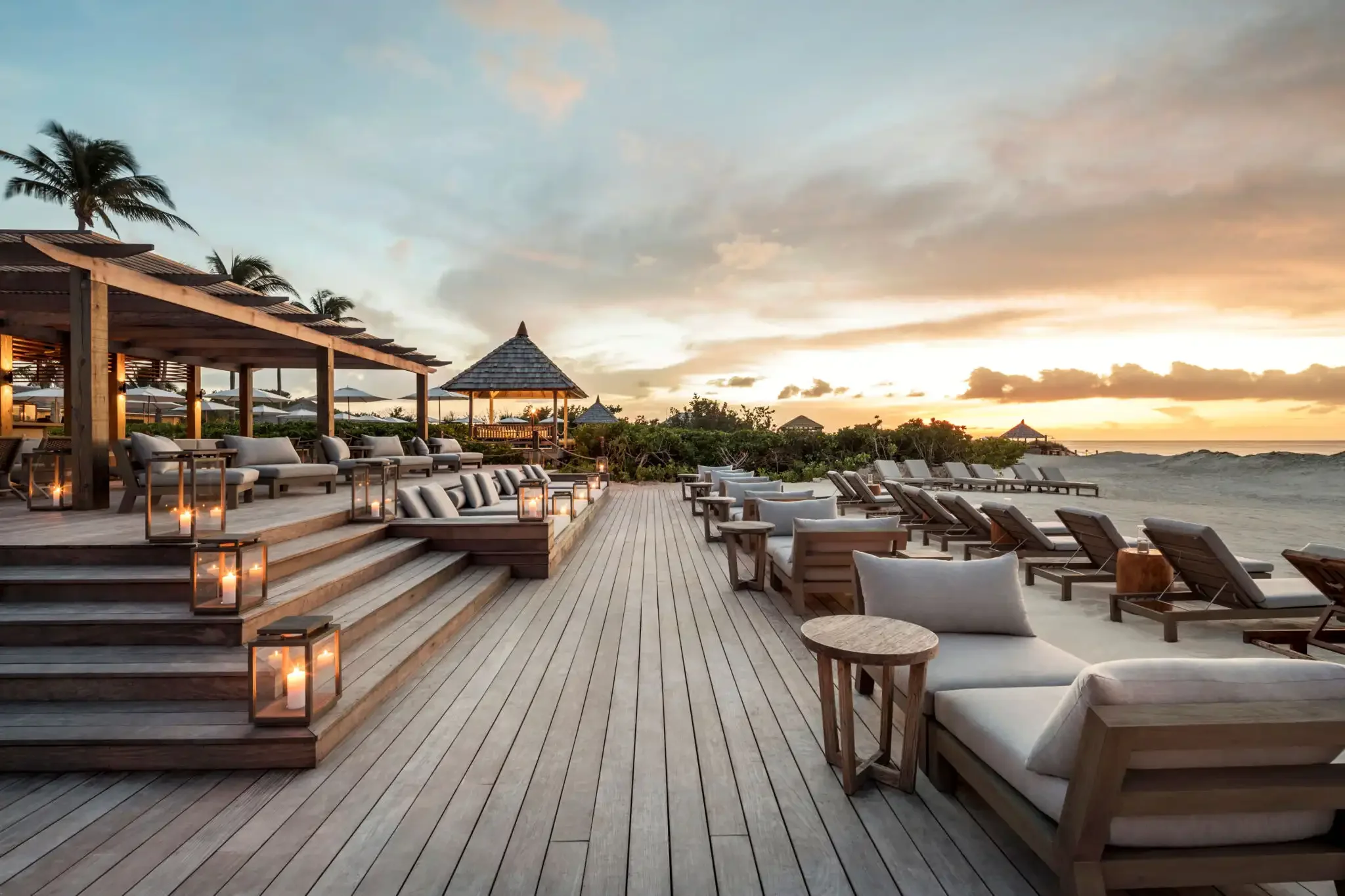 Luxury beachfront resort deck with lounge chairs and sunset view