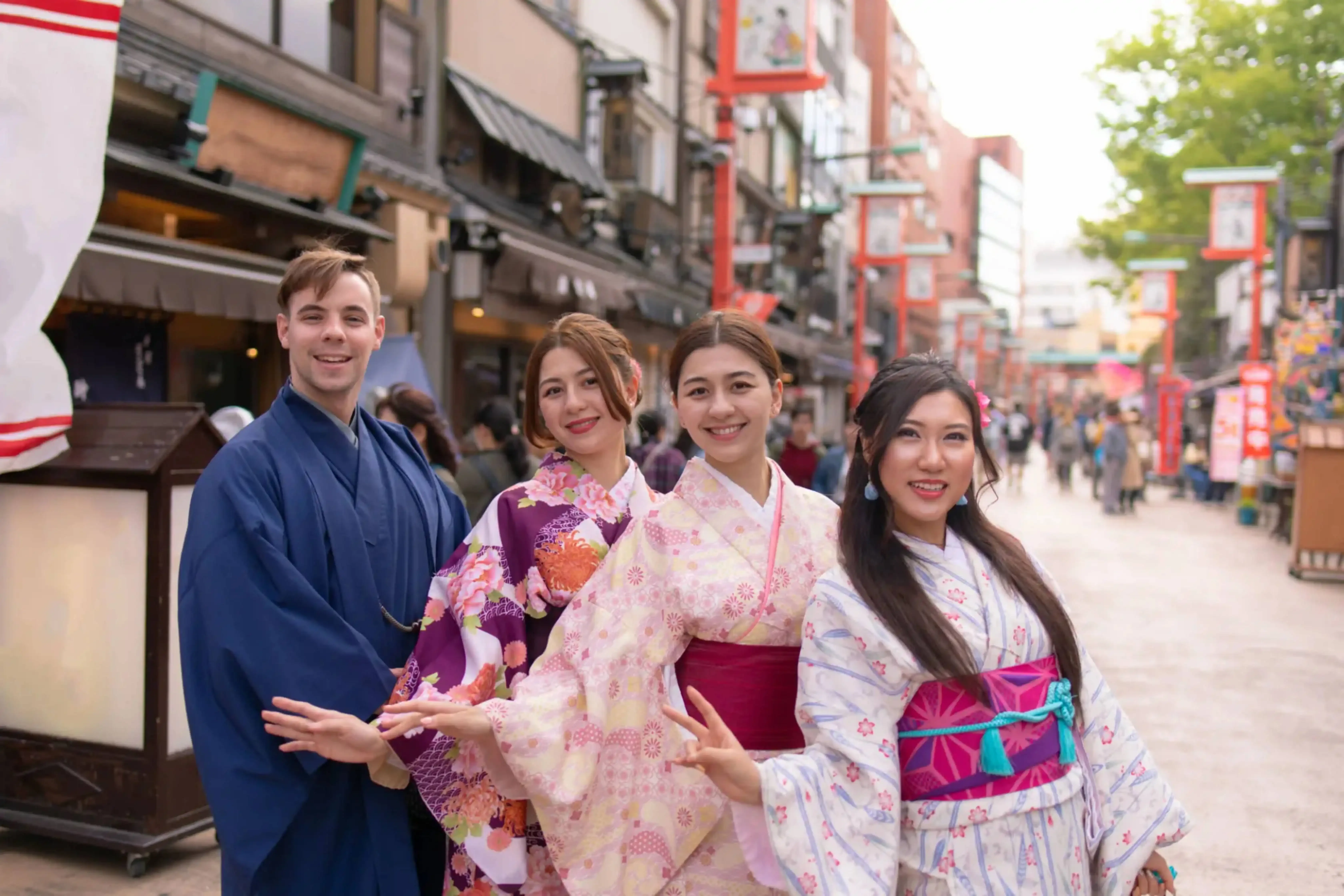Group of young travelers in colorful traditional Japanese kimonos posing on a lively street in Tokyo, Japan