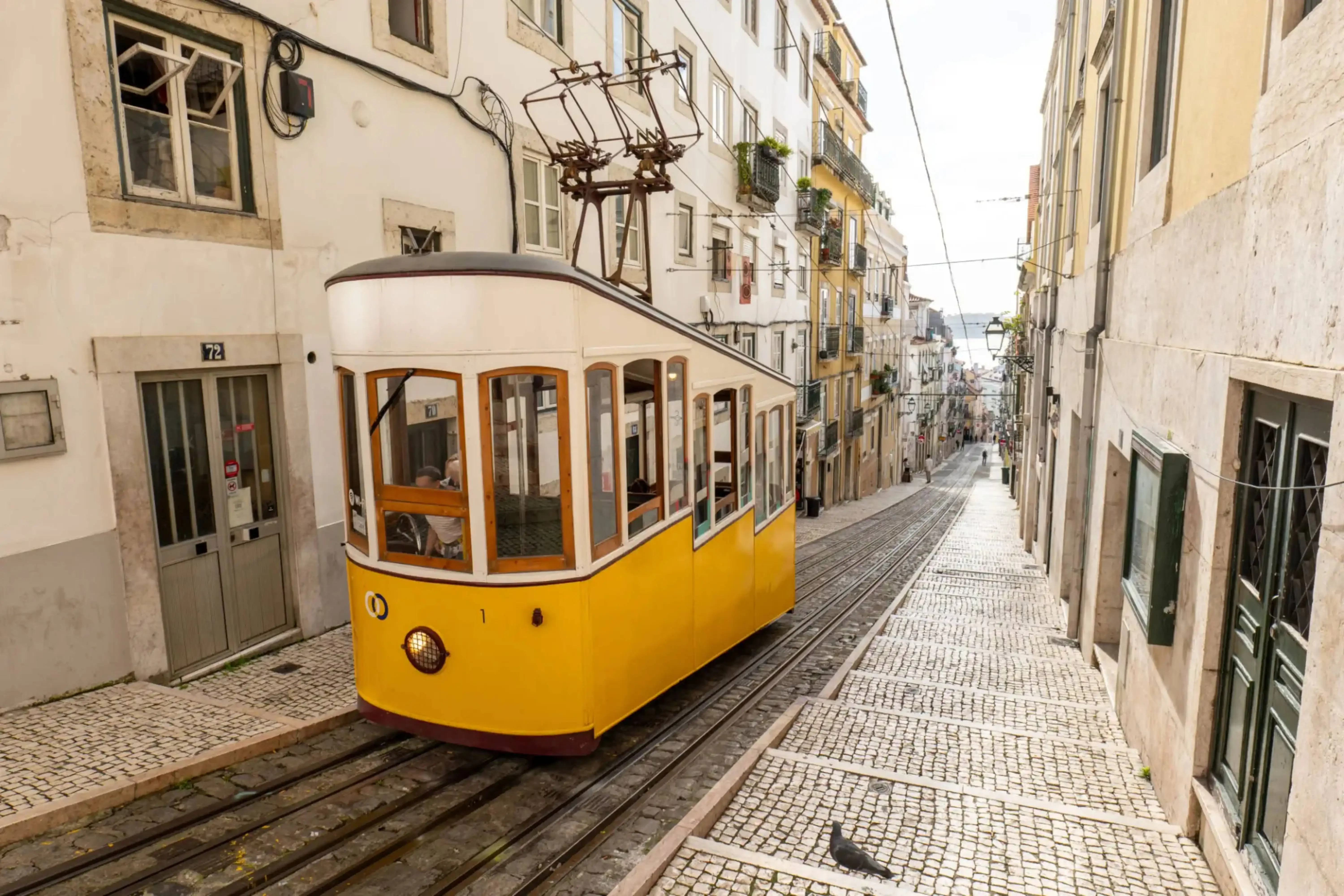 Iconic yellow tram on a steep cobblestone street in the historic Alfama district of Lisbon, Portugal