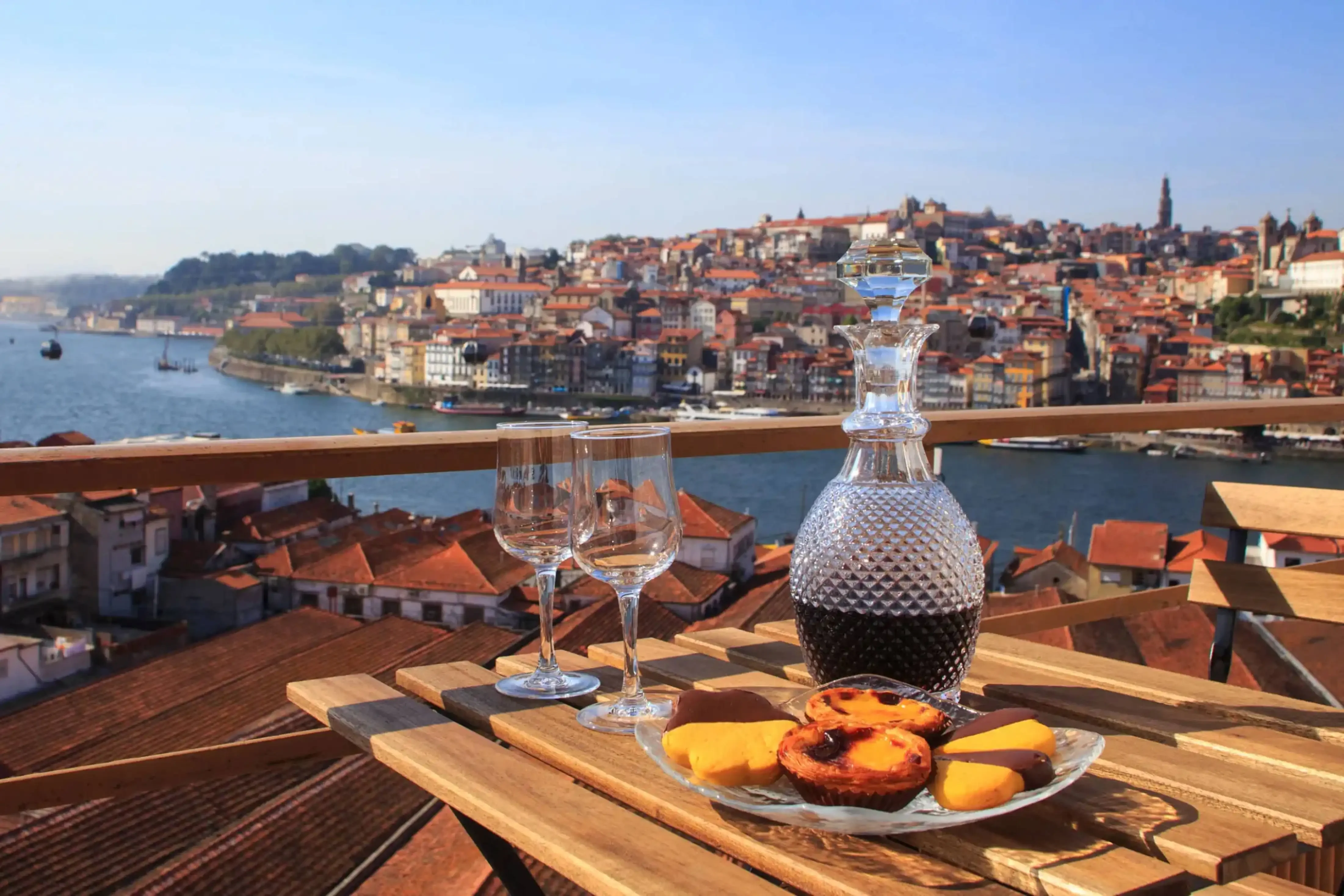 Scenic rooftop wine tasting setup overlooking a European riverside city with terracotta rooftops and historic buildings in the background