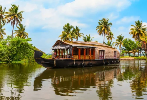 Luxury houseboat floating on serene Kerala backwaters lined with coconut palms, Kerala Tours