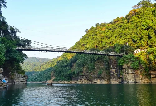 "Suspension bridge over the Dawki River surrounded by forested cliffs in Meghalaya, India"
