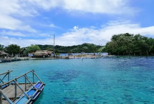 juag-fish-sanctuary-"Floating bamboo fish cage on clear blue waters surrounded by lush green hills and blue sky in Juag Lagoon"