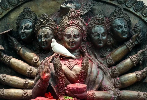 "Intricate multi-armed sculpture of Hindu goddesses with a white dove perched on the central figure"