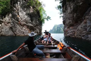 Longtail boat passing limestone cliffs at Cheow Lan Lake