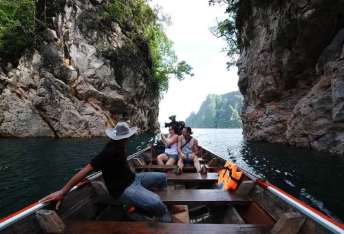 Longtail boat passing limestone cliffs at Cheow Lan Lake