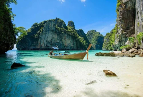 Luxury catamaran cruising beside the emerald waters of Pileh Lagoon.