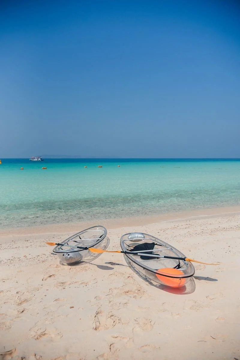 Tourists relaxing on Koh Larn Coral Island with crystal clear turquoise water near Pattaya, Thailand