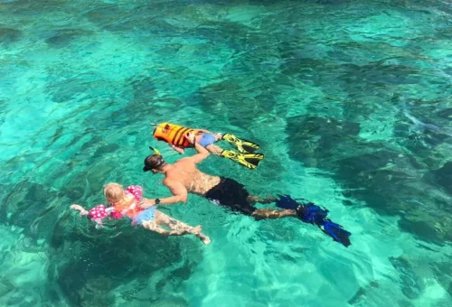 Family snorkeling in the clear waters of the Phi Phi Islands on a private speedboat tour from Phuket
