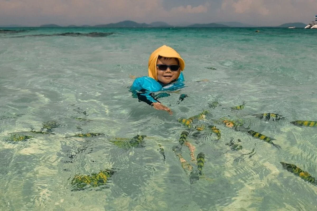 Child snorkeling in clear shallow water at Khai Islands Phuket