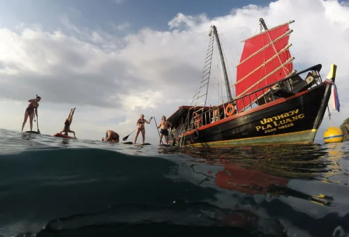 Traditional red sail boat and guests paddleboarding on the Krabi 4 Islands Cruise