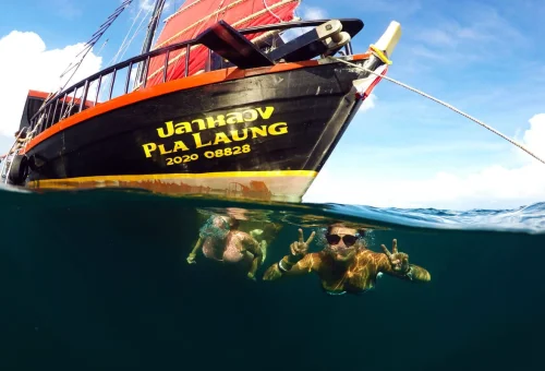 Guests swimming beside a traditional boat during the Krabi 4 Islands Sunset Cruise