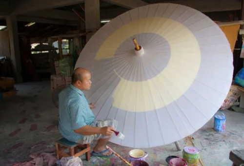 Thai artisan painting a traditional umbrella in San Kamphaeng