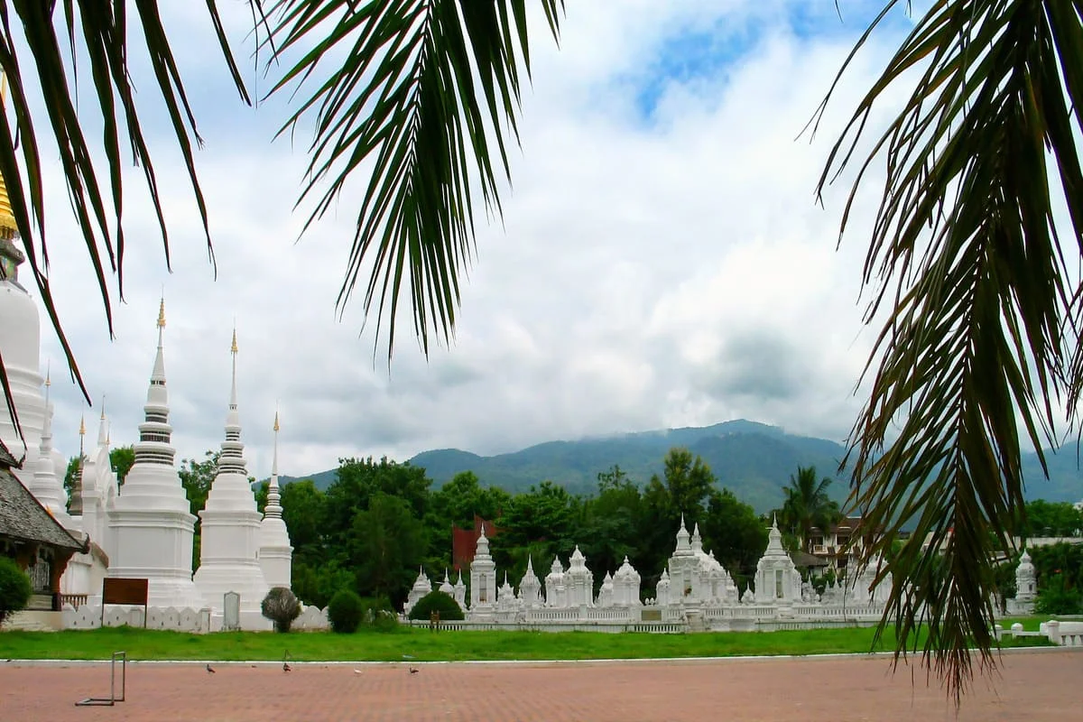 White stupas at a historic temple with mountains in Chiang Mai