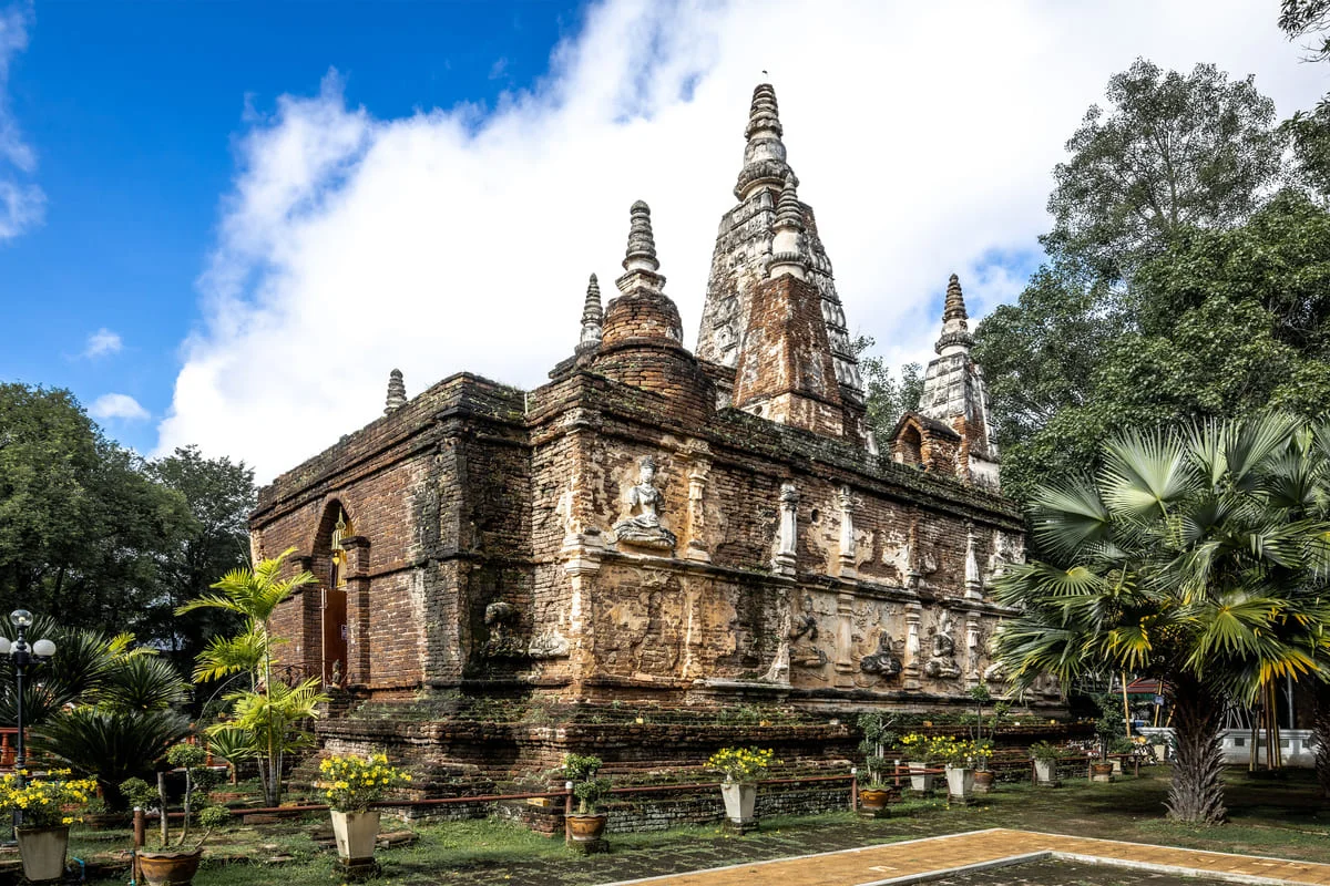 Ancient brick Buddhist chedi surrounded by trees in Chiang Mai