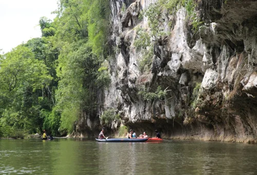 Canoes travel along the river beneath towering limestone cliffs in Khao Sok