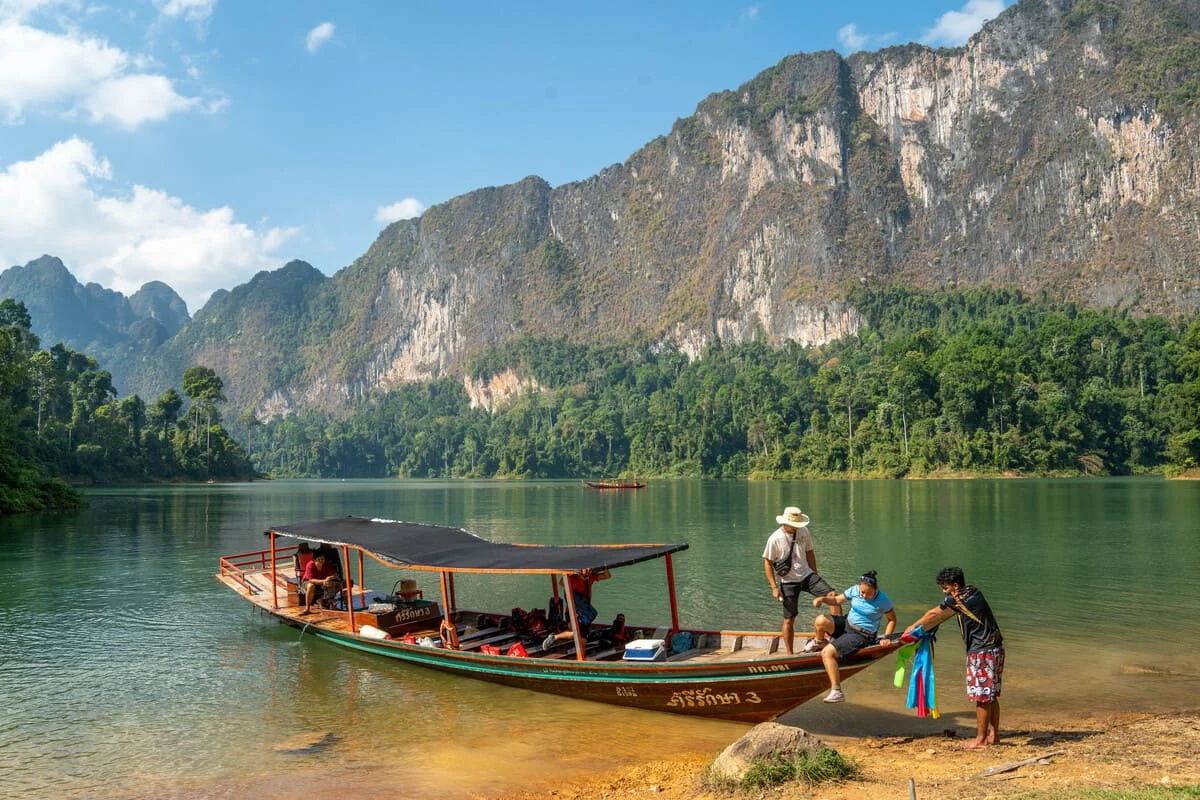Traditional longtail boat at Cheow Lan Lake surrounded by limestone cliffs in Khao Sok National Park, Thailand